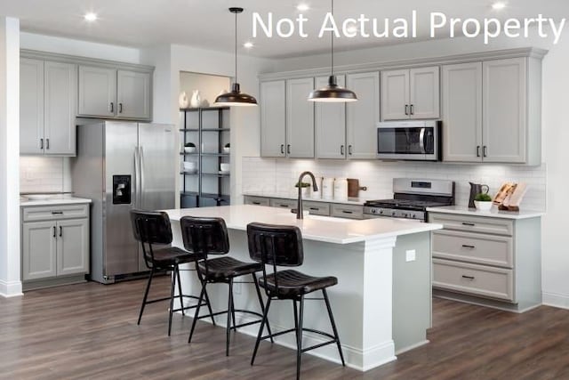 6326 Anguria Dr Lot 244, Hilliard, OH 43026 - kitchen featuring appliances with stainless steel finishes, decorative backsplash, gray cabinetry, an island with sink, and dark wood-type flooring