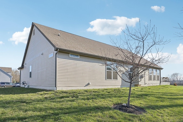 view of side of home featuring a shingled roof and a lawn
