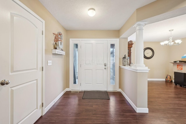foyer with dark wood-style floors, a textured ceiling, baseboards, and ornate columns