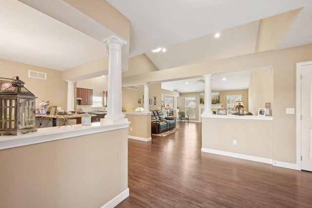 interior space featuring dark wood finished floors, visible vents, vaulted ceiling, and ornate columns