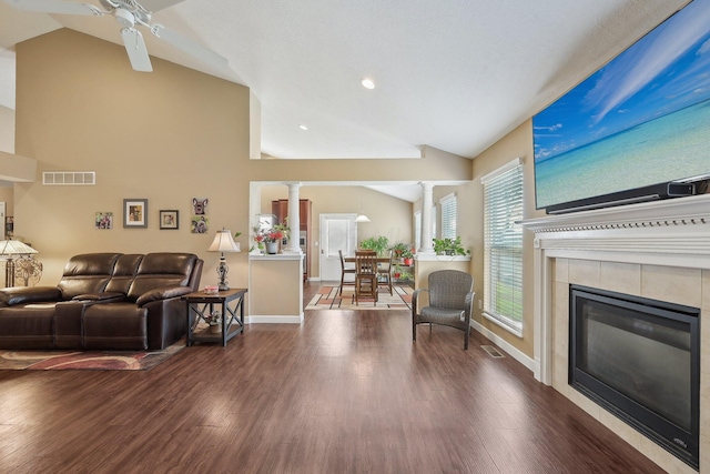 living area featuring lofted ceiling, a fireplace, visible vents, and decorative columns