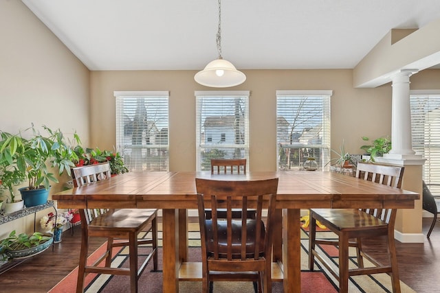 dining area with dark wood-type flooring, a healthy amount of sunlight, and decorative columns