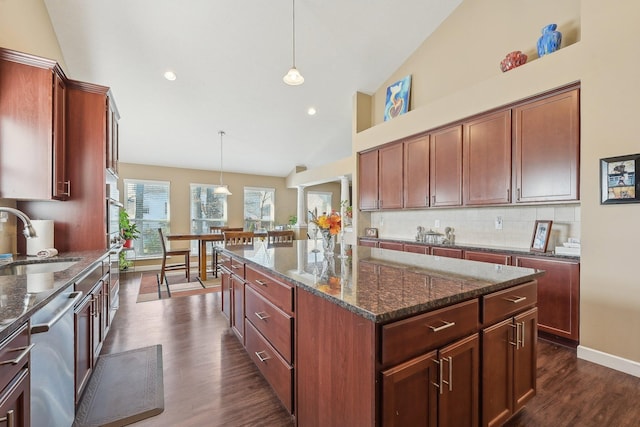kitchen featuring tasteful backsplash, dark wood finished floors, dark stone counters, a sink, and dishwasher