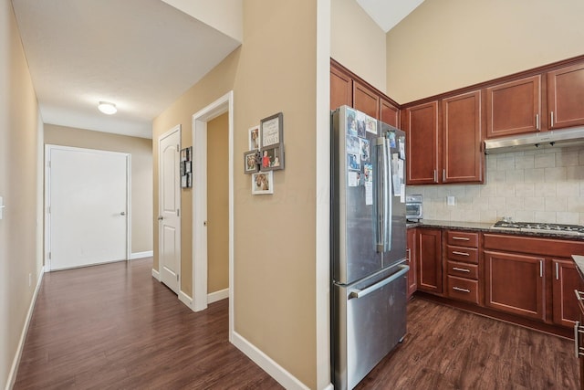 kitchen featuring under cabinet range hood, dark wood-style flooring, backsplash, and appliances with stainless steel finishes