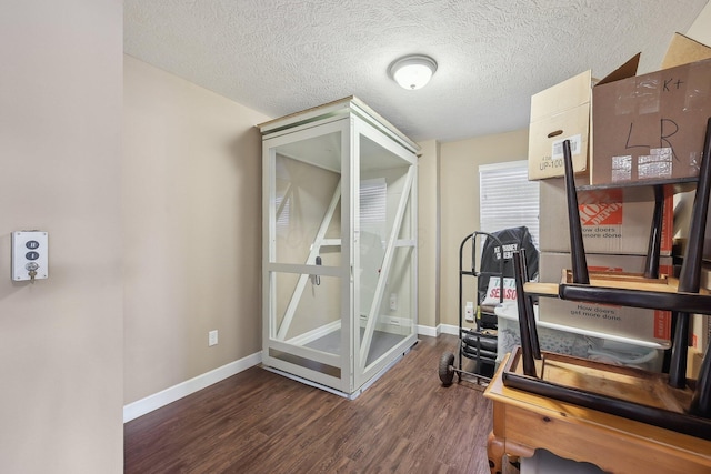 exercise area with baseboards, a textured ceiling, and wood finished floors