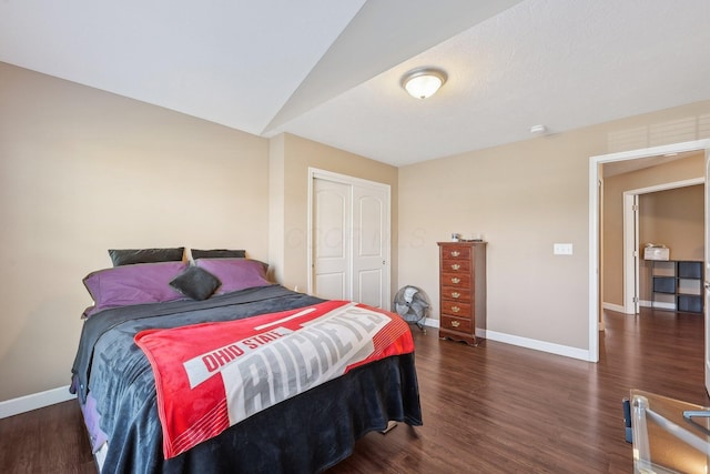 bedroom with a closet, baseboards, lofted ceiling, and wood finished floors
