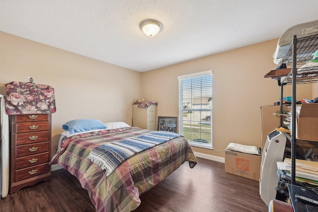 bedroom with a textured ceiling, baseboards, and wood finished floors