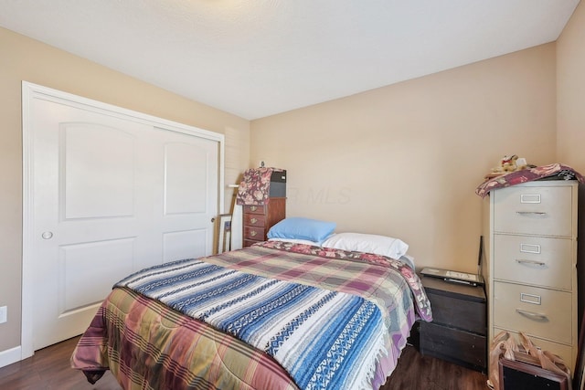 bedroom with a closet and dark wood-style flooring