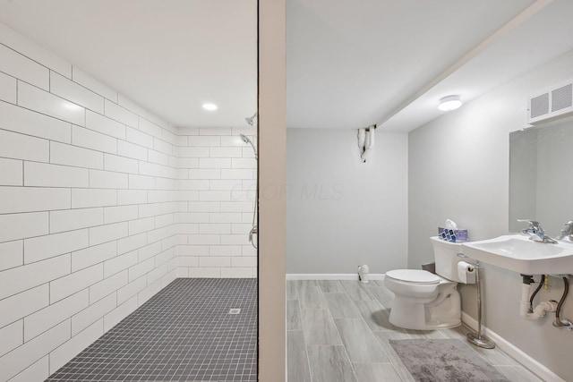 bathroom featuring toilet, baseboards, a shower stall, a sink, and visible vents