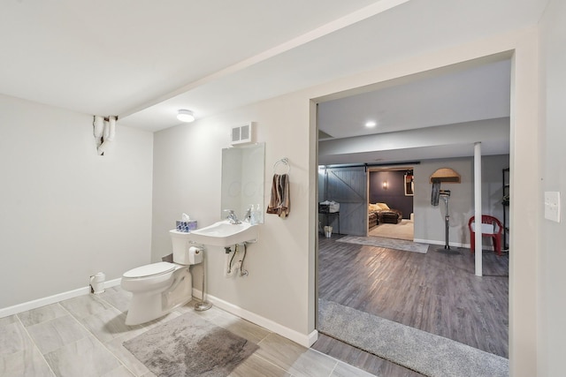 bathroom featuring baseboards, visible vents, wood finished floors, and toilet