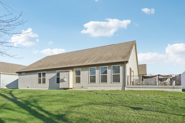 back of house with a lawn, a shingled roof, and a deck