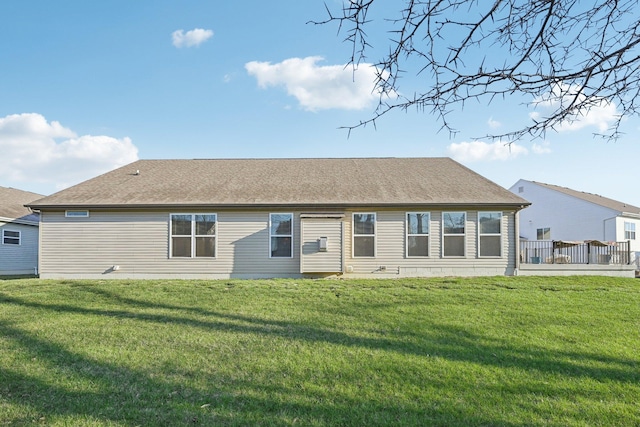 rear view of house featuring a shingled roof and a yard
