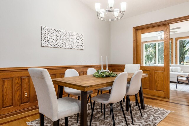 dining room with a notable chandelier, a wainscoted wall, and light wood-style floors