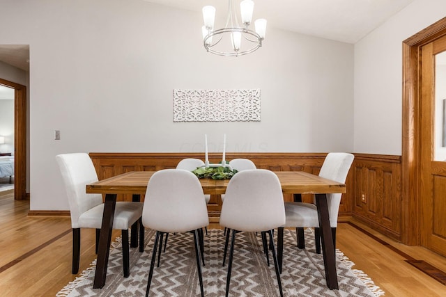dining area with light wood-type flooring, a wainscoted wall, visible vents, and a notable chandelier