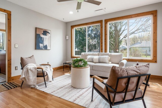 living room featuring light wood-type flooring, a ceiling fan, baseboards, and recessed lighting