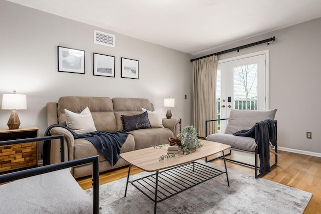 living room featuring light wood finished floors, baseboards, french doors, and visible vents