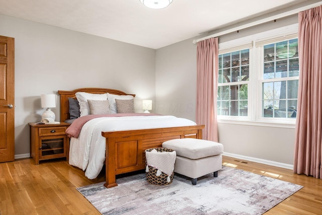 bedroom featuring baseboards, visible vents, and light wood finished floors