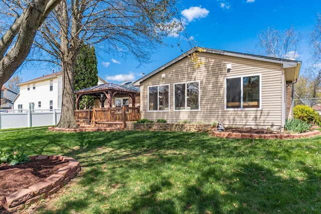 back of property featuring a gazebo, a lawn, and fence