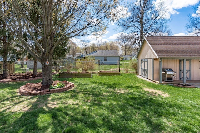 view of yard featuring fence, a garden, and an outbuilding