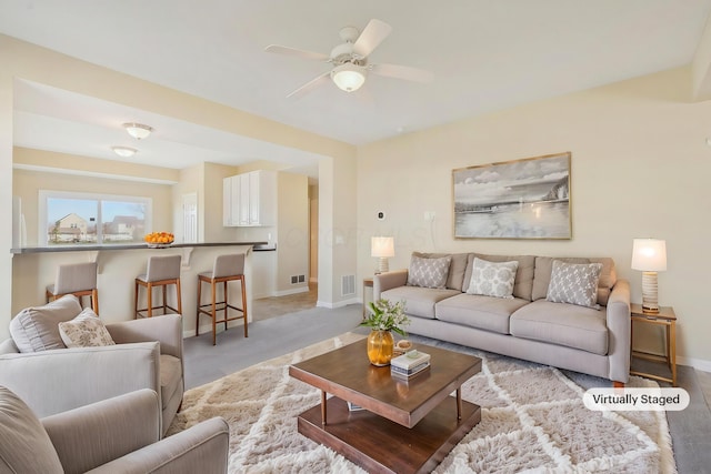 living room with light carpet, baseboards, visible vents, and a ceiling fan