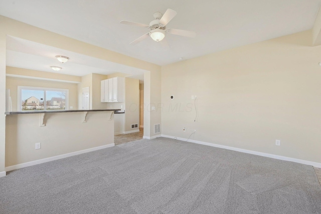 unfurnished living room featuring visible vents, light carpet, baseboards, and ceiling fan