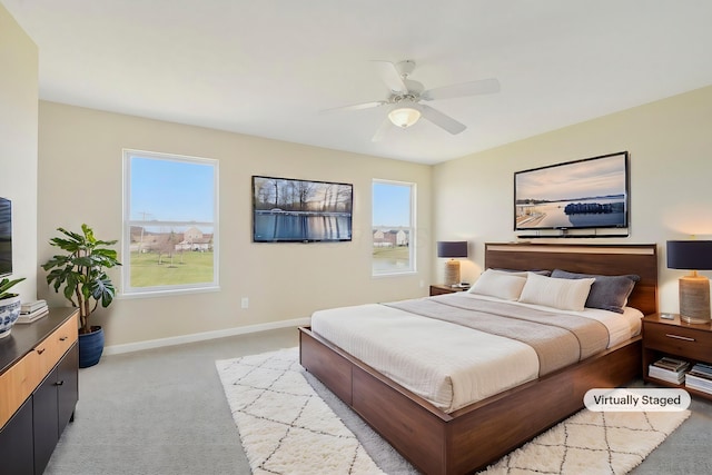 bedroom featuring baseboards, ceiling fan, multiple windows, and light colored carpet