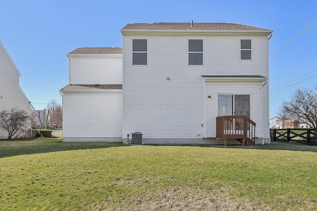 back of property with a shingled roof, central AC unit, fence, and a lawn