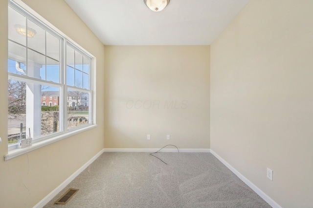 carpeted spare room with plenty of natural light, baseboards, and visible vents