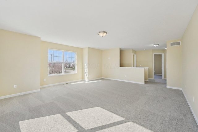 empty room with baseboards, visible vents, and carpet