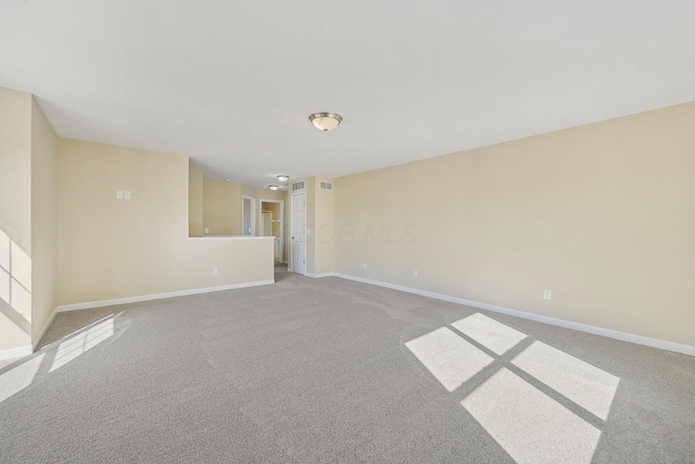 unfurnished living room featuring baseboards, visible vents, and carpet