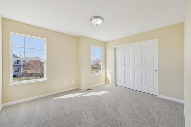 unfurnished bedroom featuring baseboards, carpet flooring, visible vents, and a closet