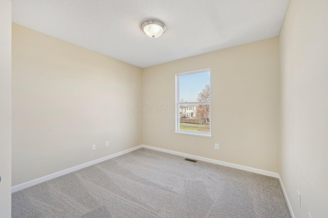 spare room featuring baseboards, visible vents, and carpet