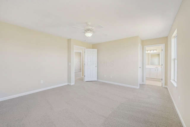 unfurnished bedroom featuring ensuite bathroom, light colored carpet, ceiling fan, and baseboards