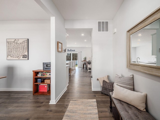 corridor featuring dark wood-type flooring, baseboards, visible vents, and recessed lighting