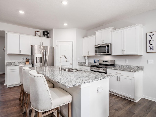 kitchen with a center island with sink, dark wood finished floors, a sink, and stainless steel appliances