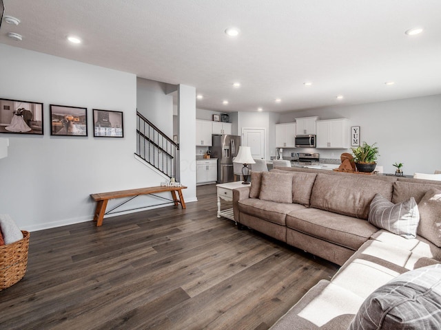 living area with baseboards, dark wood-type flooring, stairway, and recessed lighting