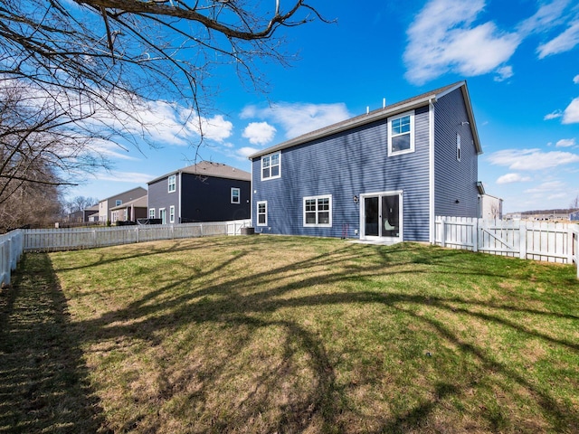 rear view of house with a fenced backyard and a lawn
