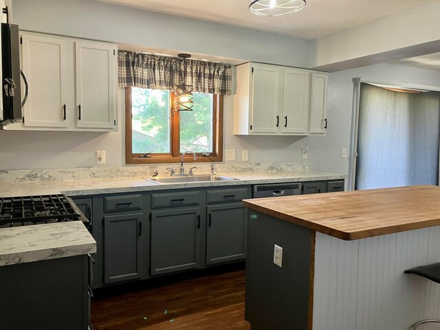 kitchen featuring stainless steel microwave, white cabinets, a sink, and wooden counters