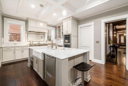 1349 E Broad St, Columbus, OH 43205 - kitchen featuring light countertops, a kitchen island with sink, dark wood-type flooring, and glass insert cabinets