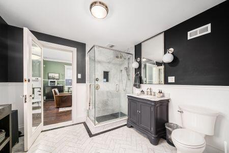 1349 E Broad St, Columbus, OH 43205 - bathroom featuring vanity, toilet, a shower stall, a wainscoted wall, and visible vents