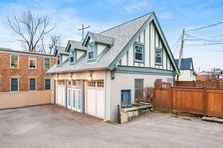 1349 E Broad St, Columbus, OH 43205 - view of side of home featuring stucco siding, fence, aphalt driveway, a garage, and a shingled roof