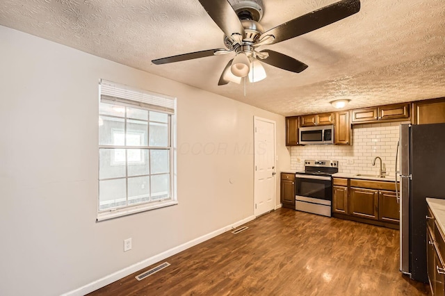 3484 Sweetday St, Columbus, OH 43224 - kitchen with stainless steel appliances, a sink, a textured ceiling, dark wood-type flooring, and baseboards