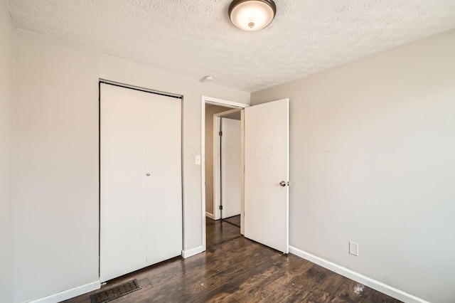 3484 Sweetday St, Columbus, OH 43224 - unfurnished bedroom with dark wood-style floors, a textured ceiling, a closet, and baseboards