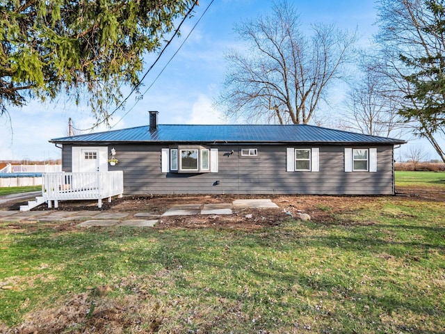 back of house featuring metal roof, a wooden deck, and a yard
