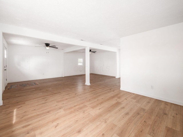 basement featuring light wood finished floors, baseboards, and ceiling fan