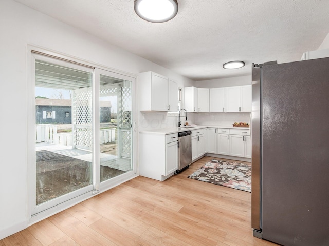 kitchen with light countertops, a sink, tasteful backsplash, appliances with stainless steel finishes, and light wood-type flooring