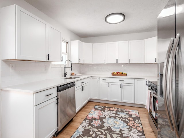 kitchen featuring a sink, white cabinets, light wood-style floors, and appliances with stainless steel finishes
