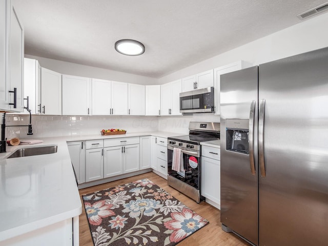 kitchen with a sink, visible vents, light wood-style floors, and appliances with stainless steel finishes