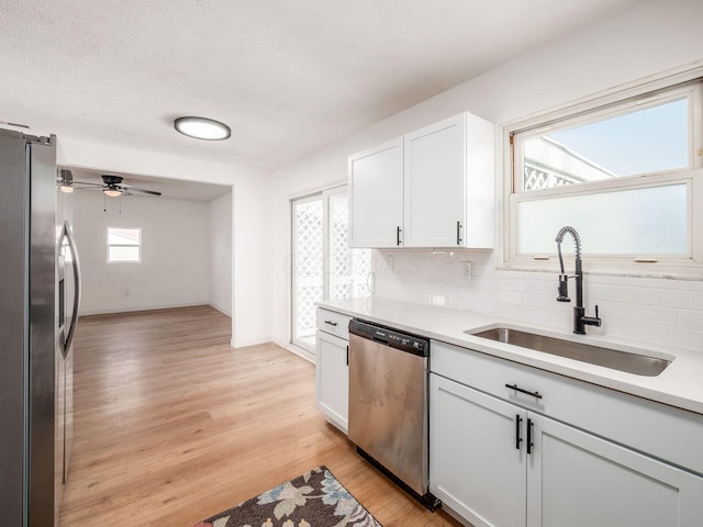 kitchen with backsplash, a sink, stainless steel appliances, and light wood finished floors