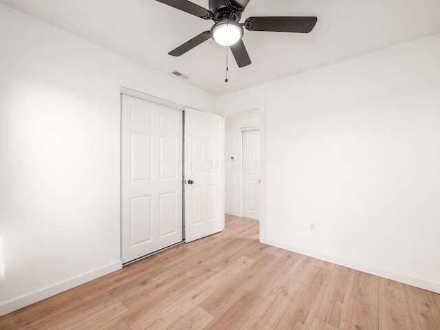 unfurnished bedroom with baseboards, light wood finished floors, ceiling fan, visible vents, and a closet